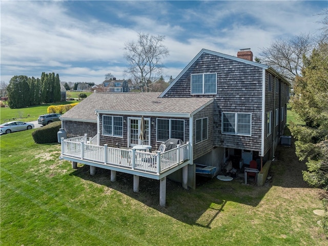 rear view of house with a shingled roof, a lawn, a chimney, cooling unit, and a wooden deck