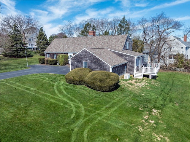 view of front of house with roof with shingles, a chimney, aphalt driveway, and a front yard