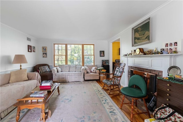 living area with crown molding, visible vents, wood finished floors, and a fireplace