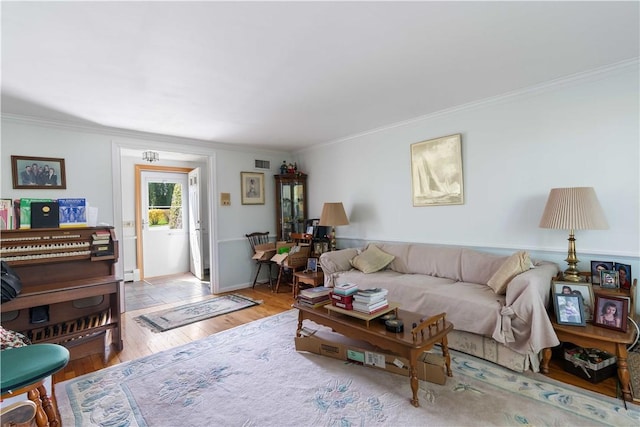 living area featuring wood finished floors, ornamental molding, and visible vents