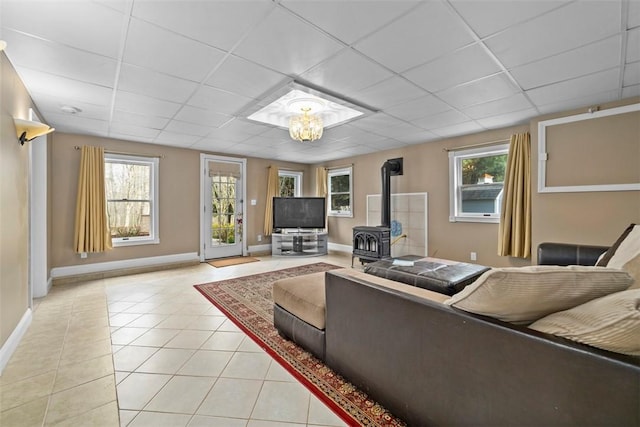 174 Windmill Dr, South Kingstown, RI 02879 - living area featuring a healthy amount of sunlight, a paneled ceiling, a wood stove, baseboards, and light tile patterned flooring