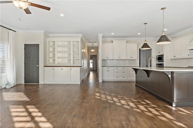 kitchen with stainless steel microwave, ornamental molding, and dark wood-style flooring