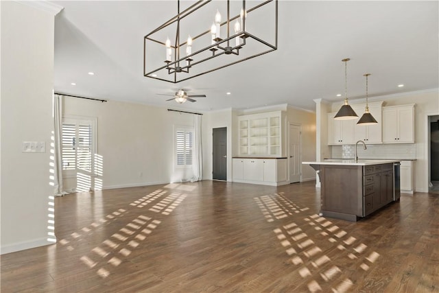 interior space with tasteful backsplash, open floor plan, light countertops, a kitchen island with sink, and ceiling fan with notable chandelier