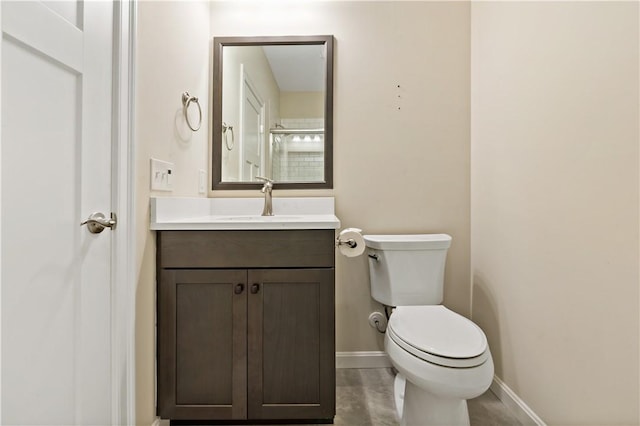 bathroom with toilet, vanity, and baseboards