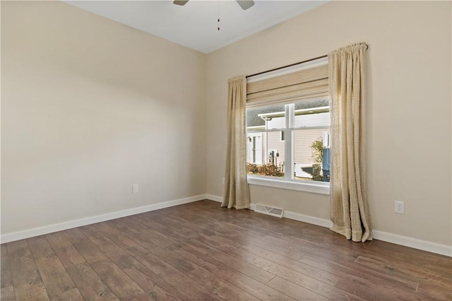 spare room with dark wood-type flooring, visible vents, baseboards, and a ceiling fan