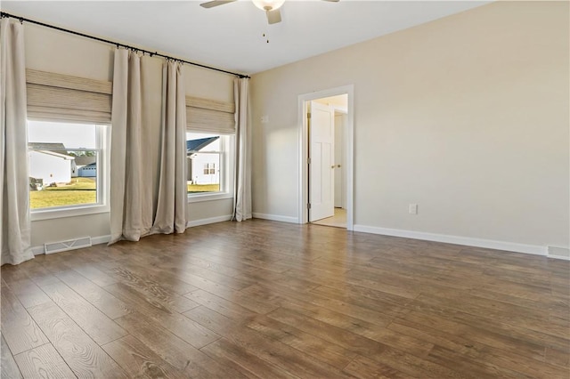 empty room featuring hardwood / wood-style floors, ceiling fan, baseboards, and visible vents