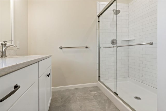 bathroom with baseboards, a stall shower, and vanity