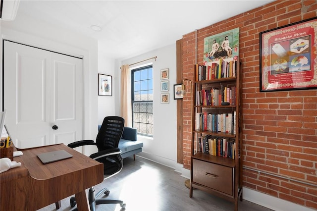 office space with brick wall, baseboards, and wood finished floors