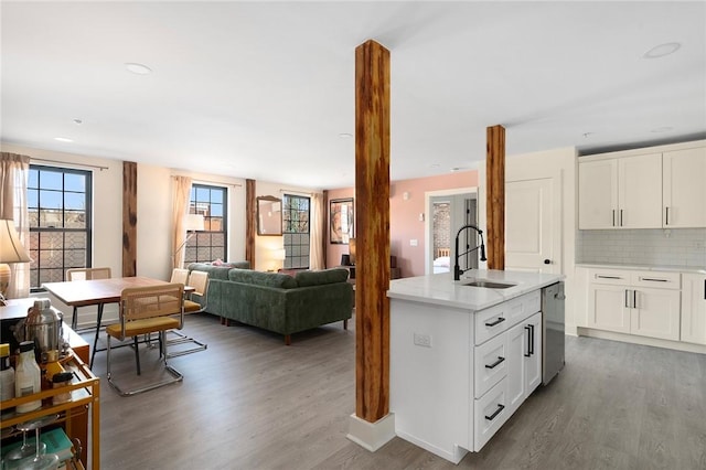 kitchen with tasteful backsplash, dishwasher, a sink, open floor plan, and wood finished floors