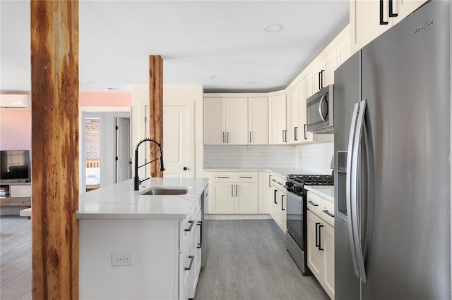 kitchen with a sink, a kitchen island with sink, stainless steel appliances, decorative backsplash, and a wall unit AC