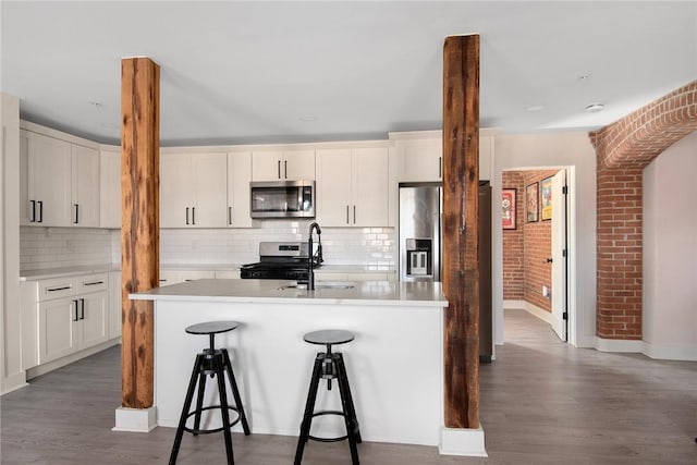 kitchen with a sink, an island with sink, wood finished floors, and stainless steel appliances