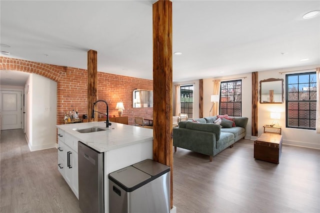 kitchen with dishwasher, baseboards, a sink, and light wood-style flooring