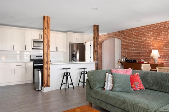 living room with brick wall and wood finished floors