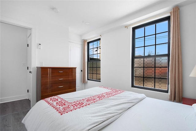 bedroom with a closet, baseboards, and dark wood finished floors