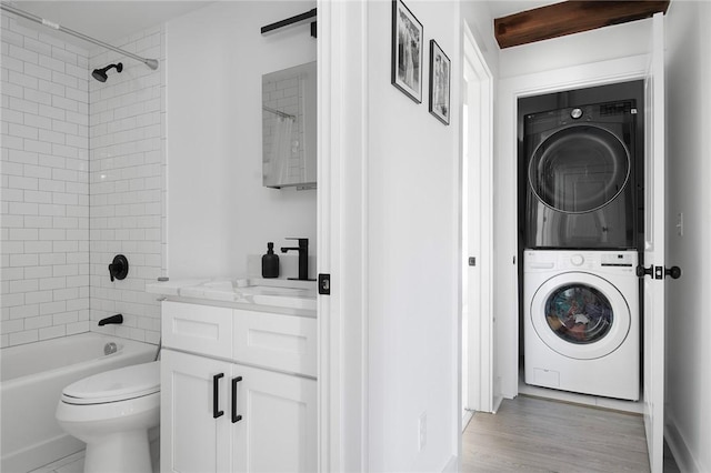 laundry room with light wood-style floors and stacked washer / dryer