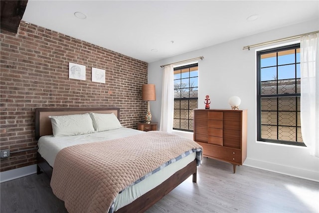 bedroom featuring brick wall, recessed lighting, baseboards, and wood finished floors