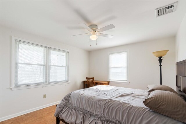 bedroom with baseboards, visible vents, light wood-style floors, and multiple windows