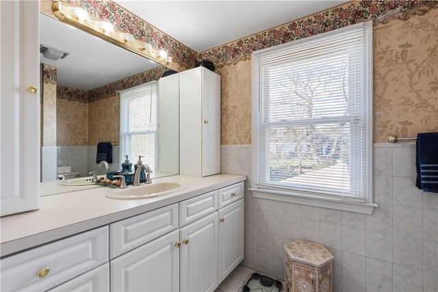 bathroom featuring plenty of natural light, wallpapered walls, and tile walls