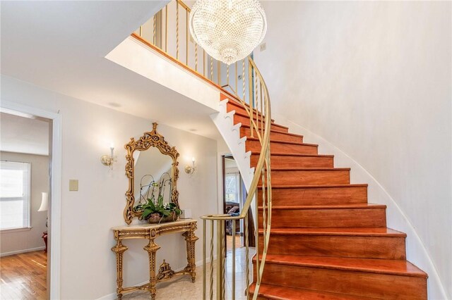 stairway featuring baseboards, wood finished floors, and a chandelier
