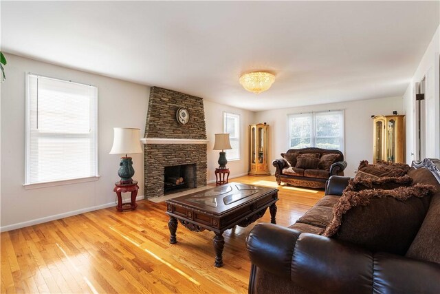 living room with baseboards, a fireplace, and light wood-style flooring