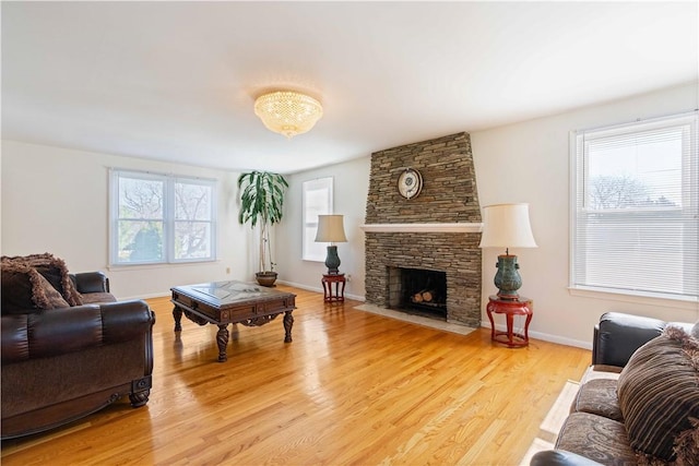 living area featuring a fireplace, baseboards, and light wood-type flooring