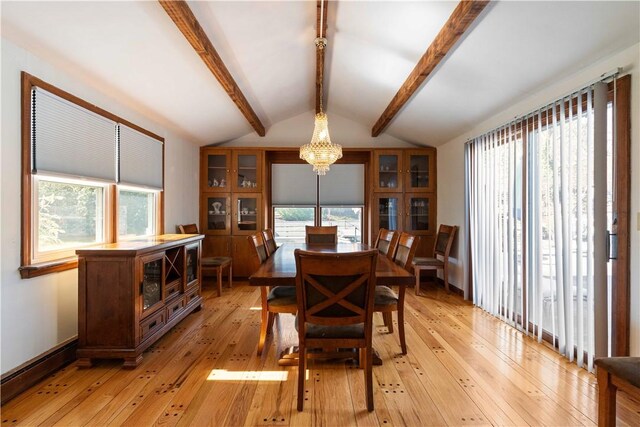 dining room featuring lofted ceiling with beams, an inviting chandelier, and light wood-style floors