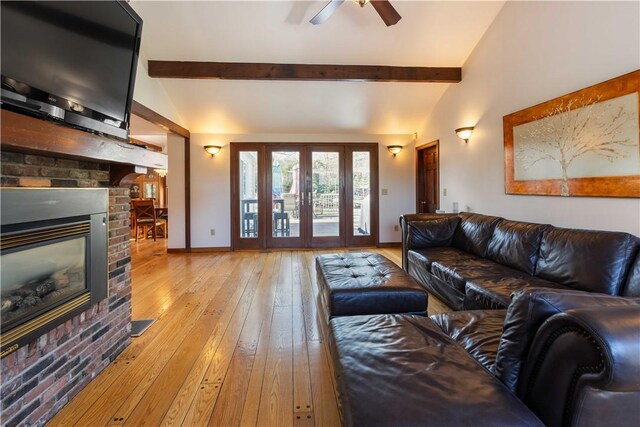 living room featuring ceiling fan, lofted ceiling with beams, hardwood / wood-style floors, baseboards, and a brick fireplace