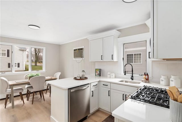 kitchen featuring dishwasher, a sink, a wall mounted AC, a peninsula, and light wood finished floors
