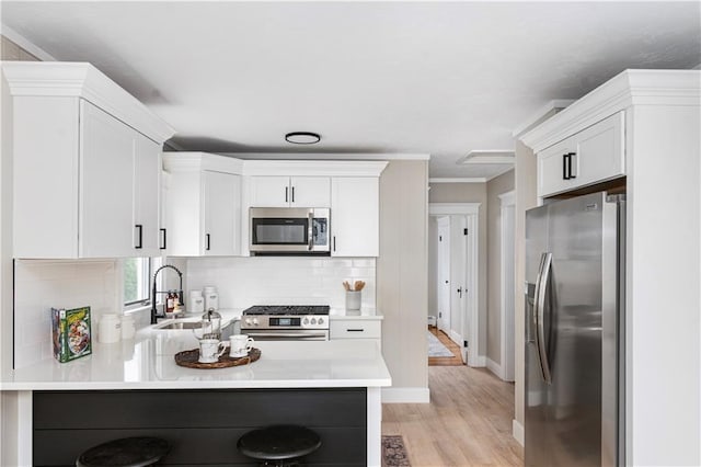 kitchen featuring light wood-style flooring, tasteful backsplash, a peninsula, appliances with stainless steel finishes, and light countertops