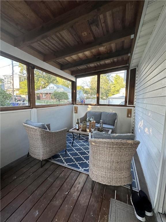 sunroom / solarium with a healthy amount of sunlight, an outdoor hangout area, and beamed ceiling
