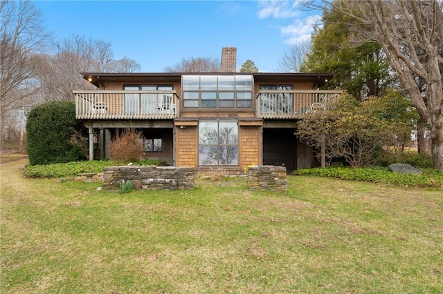 rear view of property with a wooden deck, a chimney, and a lawn