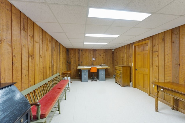 interior space featuring wood walls and a drop ceiling