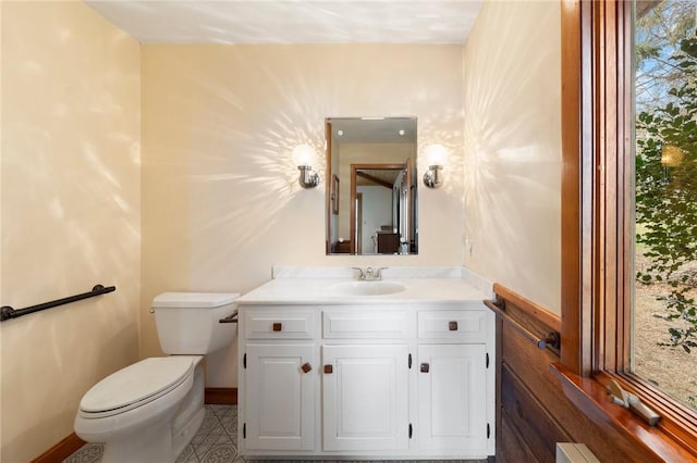 bathroom with toilet, vanity, and baseboards