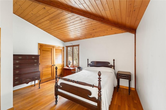 bedroom with a closet, vaulted ceiling, wood ceiling, wood finished floors, and baseboards
