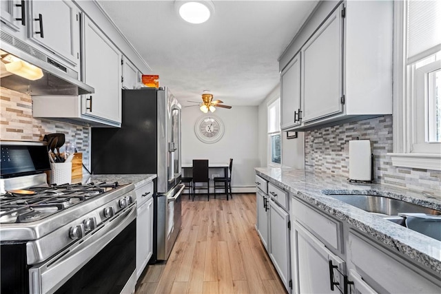 kitchen with a healthy amount of sunlight, ceiling fan, stainless steel range with gas cooktop, and under cabinet range hood