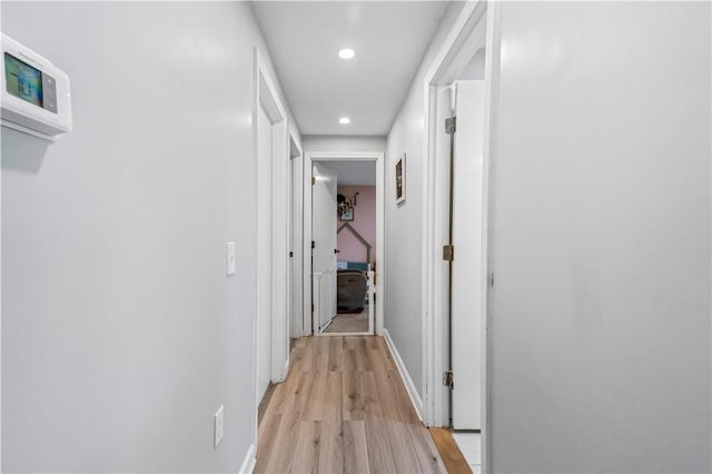 hallway with recessed lighting, light wood finished floors, and baseboards