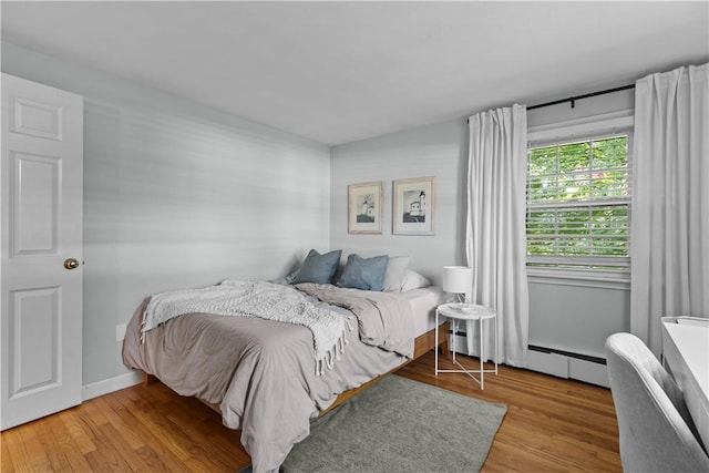 bedroom featuring baseboards, wood finished floors, and baseboard heating