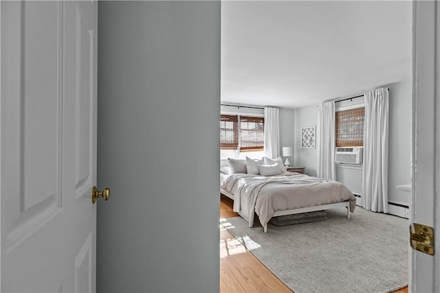 bedroom featuring a baseboard radiator, cooling unit, and wood finished floors