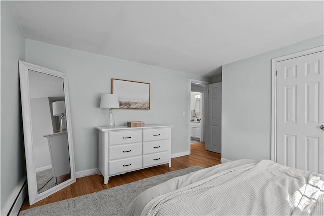 bedroom with baseboard heating, baseboards, and wood finished floors
