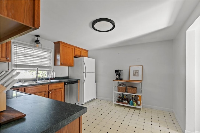 kitchen featuring dark countertops, dishwasher, a sink, and light floors