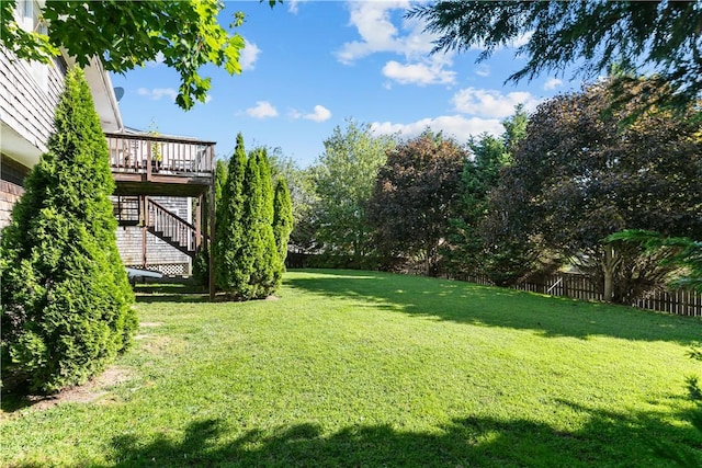 view of yard featuring fence, a deck, and stairs