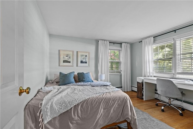bedroom featuring a baseboard heating unit and wood finished floors