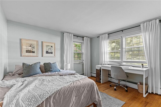 bedroom with a baseboard radiator and wood finished floors