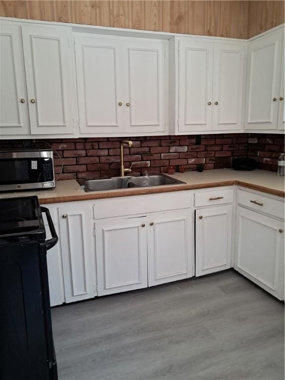 25 Wilson St, West Warwick, RI 02893 - kitchen featuring stainless steel microwave, black electric range, white cabinetry, and a sink
