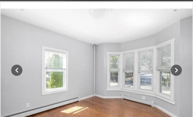 spare room with a baseboard radiator, plenty of natural light, and wood finished floors