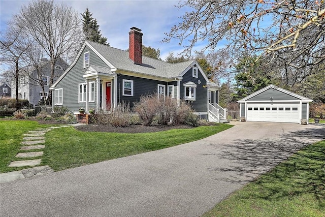 view of front facade featuring a front lawn, a chimney, an outbuilding, and a detached garage