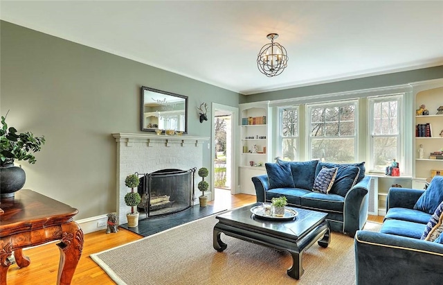 living room featuring built in shelves, a brick fireplace, and wood finished floors