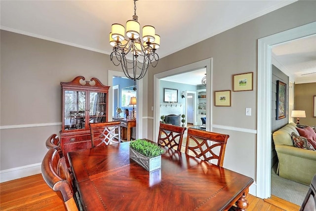 dining room with ornamental molding, baseboards, a notable chandelier, and wood finished floors
