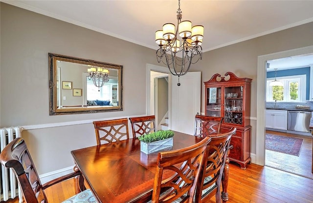 dining space featuring a chandelier, light wood finished floors, and ornamental molding