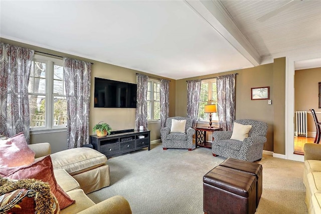 living area with beamed ceiling, baseboards, and light colored carpet